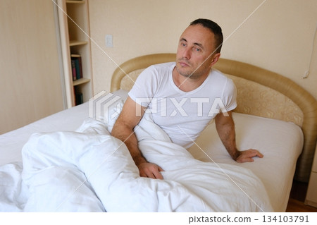 Man waking bed man wearing sleepwear waking up in bed and stretching his arms in bedroom at home. male person doing morning exercises for health indoors Man waking bed man wearing sleepwear waking up in bed and stretching his arms in bedroom at home. male person doing morning exercises for health indoors 134103791