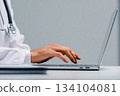 Closeup of medical doctor in uniform working at desk in office typing on laptop 134104081