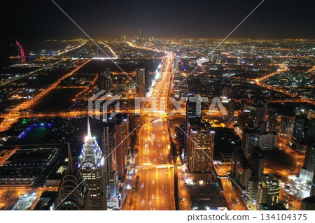 Aerial night view of Dubai skyline. Illuminated Sheikh Zayed Road highway traffic and modern skyscrapers in United Arab Emirates city center. 134104375