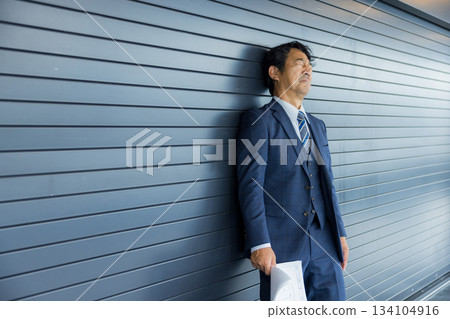 一位商人站在店鋪前沉思。 一位商人站在店鋪前沉思。 134104916