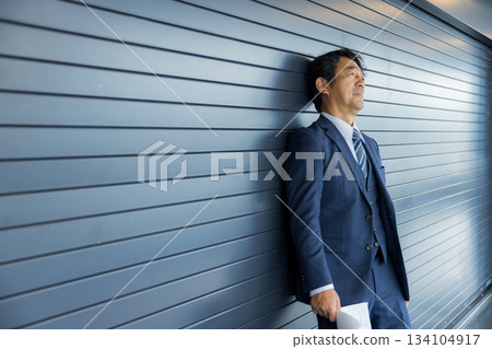 一位商人站在店鋪前沉思。 一位商人站在店鋪前沉思。 134104917