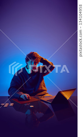 Young man scratching head while evaluating online casino session. 134104958