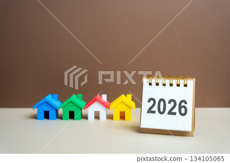 Inscription 2026 and miniature houses. Family budget planning for next year. Investments, plans, savings. Mortgage rates. Real estate concept. Refinance home. 134105065