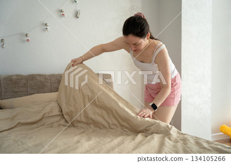 A caucasian woman made her bed in her bedroom on a sunny day. morning routine A caucasian woman made her bed in her bedroom on a sunny day. morning routine 134105266