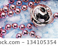 Christmas bell and pink festive beads on blue snow background 134105354