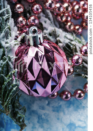 Pink Christmas ornament with beads on snowy winter background 134105456