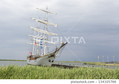 Sailing ship docked at Marker Wadden harbour in the Netherlands on a cloudy day with flags fluttering in the wind Sailing ship docked at Marker Wadden harbour in the Netherlands on a cloudy day with flags fluttering in the wind 134105766