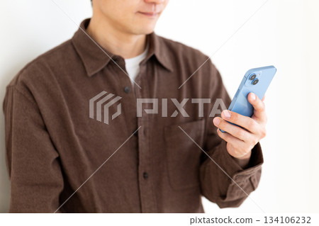 一位身著休閒裝的中年男子正在查看他的智慧型手機 134106232