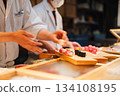 Chefs prepare sushi for customers at a restaurant 134108195