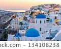 Oia Santorini sunset. People admire iconic blue domed churches and caldera views 134108238