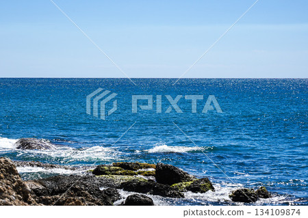 A Tranquil Coastal Scene Capturing the Vibrant Blue Waters and Rugged Rocks Under a Clear Sky A Tranquil Coastal Scene Capturing the Vibrant Blue Waters and Rugged Rocks Under a Clear Sky 134109874