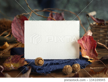 Card on wood near autumn dried leaves closeup, wedding and party mockup in blue, red and orange Card on wood near autumn dried leaves closeup, wedding and party mockup in blue, red and orange 134109945
