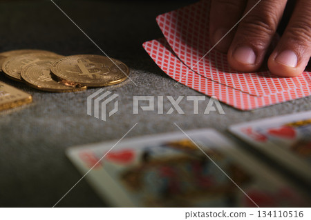 Hand holding playing cards with golden bitcoins on table 134110516