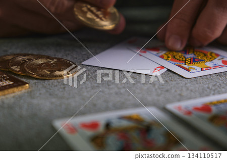 Hand placing bitcoin token on playing cards table Hand placing bitcoin token on playing cards table 134110517