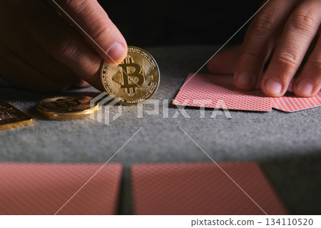 Hand holding bitcoin coin playing cards on casino table Hand holding bitcoin coin playing cards on casino table 134110520