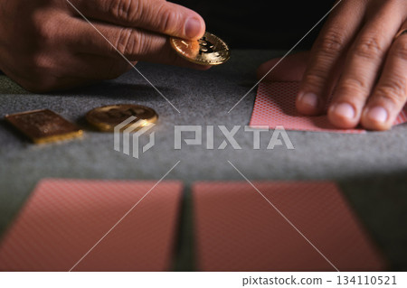 Hand placing bitcoin token on playing cards table Hand placing bitcoin token on playing cards table 134110521