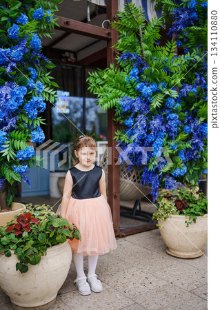 Girl in a dress stands by blue floral decorations outside Girl in a dress stands by blue floral decorations outside 134110880