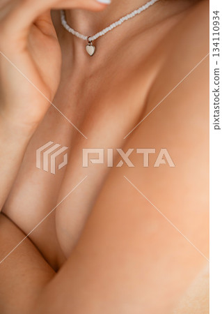 Close-up of a woman's neck and shoulder with delicate jewelry in soft light Close-up of a woman's neck and shoulder with delicate jewelry in soft light 134110934