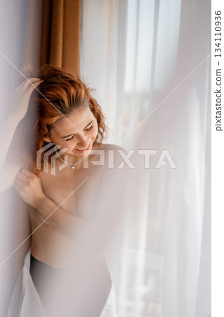 Woman peacefully enjoying a bright moment by the window Woman peacefully enjoying a bright moment by the window 134110936
