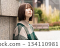 A woman posing in front of a building wall 134110981