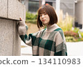 A woman posing in front of a building wall 134110983