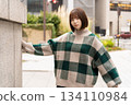 A woman posing in front of a building wall 134110984