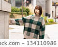 A woman posing in front of a building wall 134110986