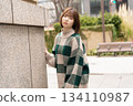 A woman posing in front of a building wall 134110987