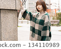 A woman posing in front of a building wall 134110989