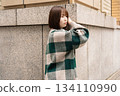 A woman posing in front of a building wall 134110990