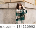 A woman posing in front of a building wall 134110992