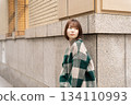 A woman posing in front of a building wall 134110993