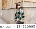 A woman posing in front of a building wall 134110995