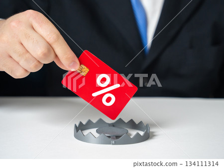 A businessman takes the credit card as bait from a trap. High interest rates and an unreliable bank. Concept for financial risk awareness, debt traps and consumer protection in banking. A businessman takes the credit card as bait from a trap. High interest rates and an unreliable bank. Concept for financial risk awareness, debt traps and consumer protection in banking. 134111314