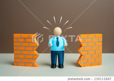 An office worker breaks down a wall. Overcoming barriers and obstacles to achieve progress. Workplace innovation and determination. Leadership content, productivity improvements and motivation An office worker breaks down a wall. Overcoming barriers and obstacles to achieve progress. Workplace innovation and determination. Leadership content, productivity improvements and motivation 134111687