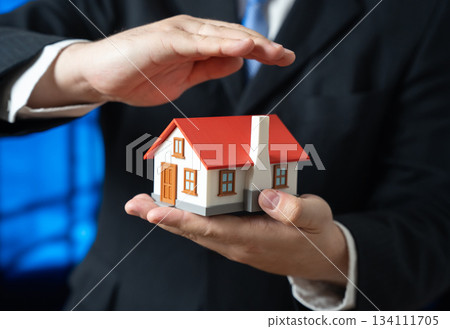 A man protects a house in his hands. Home insurance. Affordable housing. Property safety and family security. Mortgage services, real estate consulting and financial protection 134111705