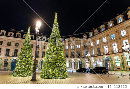 Illuminated Christmas trees stand in Place Vendome at night in Paris, France. Historic square is known for famous luxury boutiques and elegant classical architecture 134112313