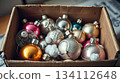A collection of retro ornaments lies packed in a worn festive box. Memory, warmth, and sentimental seasonal spirit. 134112648