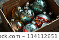 Vintage Christmas toys rest inside a simple cardboard box. Nostalgia and the charm of old holiday traditions. 134112651
