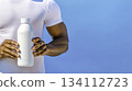 Man Holding White Bottle Against Bright Blue Background in Sunny Day 134112723