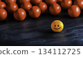 Bright Orange Ball with Happy Face Surrounded by Red Balls on Dark Background 134112725