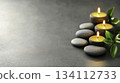 Tranquil Spa Scene with Candles, Stones, and Green Leaves on a Grey Surface 134112733