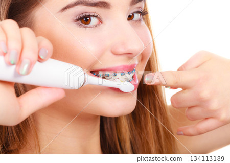 Woman smiling cleaning teeth with braces 134113189