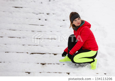 Woman tying sport shoes during winter Woman tying sport shoes during winter 134113206