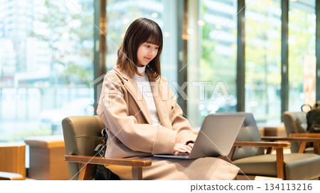 A woman using a computer in a cafe 134113216