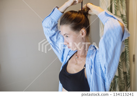 Female sports player securing her hair before training session Female sports player securing her hair before training session 134113241