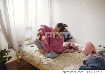 white teenage girl unboxing pink controller in bedroom 134113244