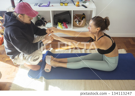 woman receiving partner assist stretch from male coach 134113247