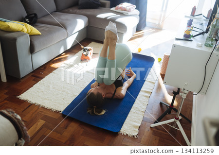 caucasian woman performing core inversion with curious dog 134113259