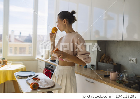 caucasian woman grabbing orange snack, nutrition student 134113293
